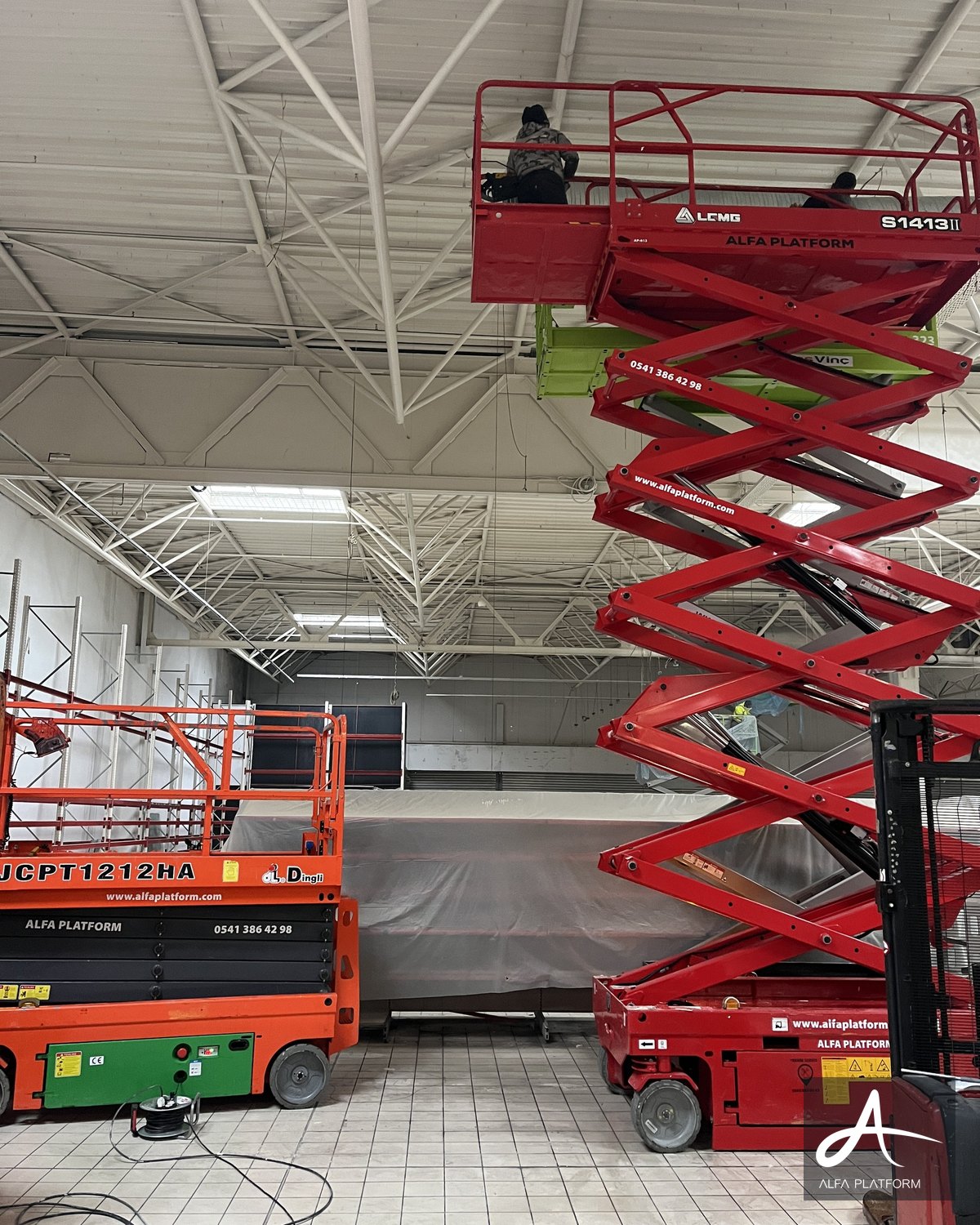 İç mekanda iki makaslı platform ve bir forklift ile çalışma yapılıyor.