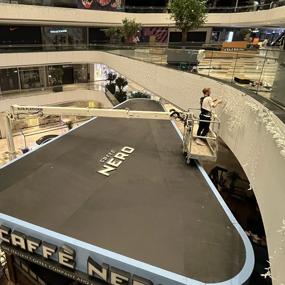 Alışveriş merkezinde platform sepetinden çalışan teknisyen